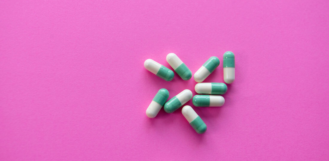 Medication capsules on pink background