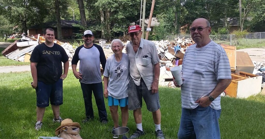 A group of volunteers in front of home damage