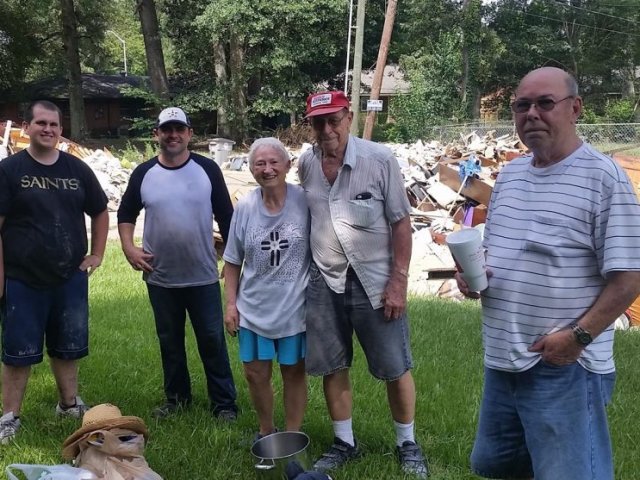 A group of volunteers in front of home damage