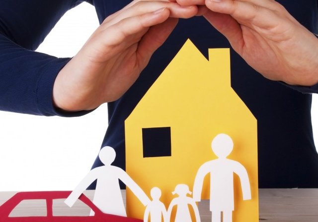 Man holding hands over paper house, people, and car