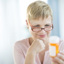 Woman with glasses holding prescription bottle