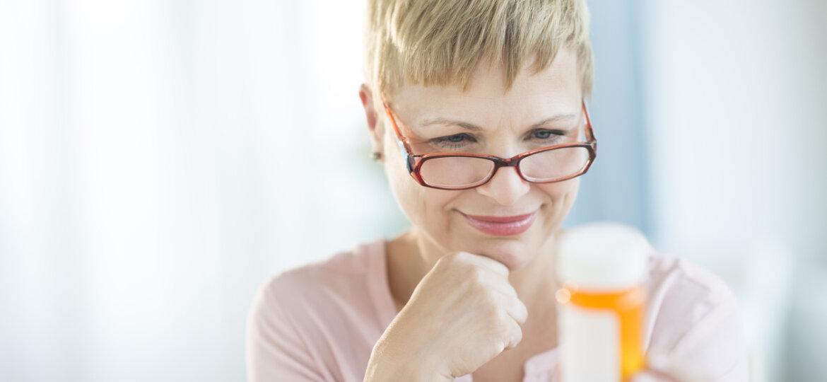 Woman with glasses holding prescription bottle