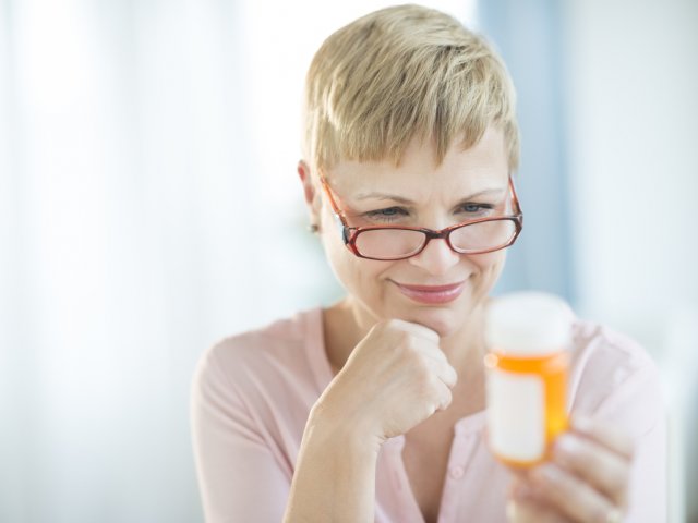 Woman with glasses holding prescription bottle