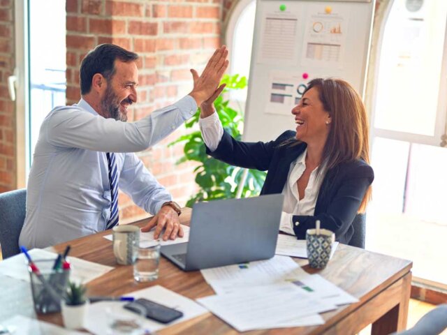 Man and woman giving high five at desk