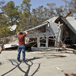 Man in front of damaged home