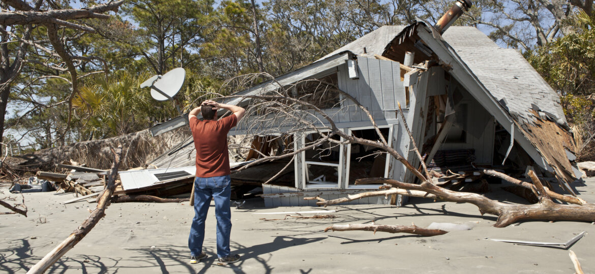 Man in front of damaged home