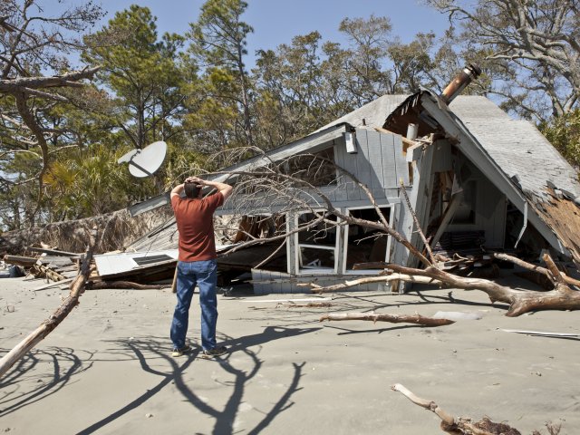 Man in front of damaged home