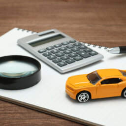 Toy car, magnifying glass, calculator, pen and notebook