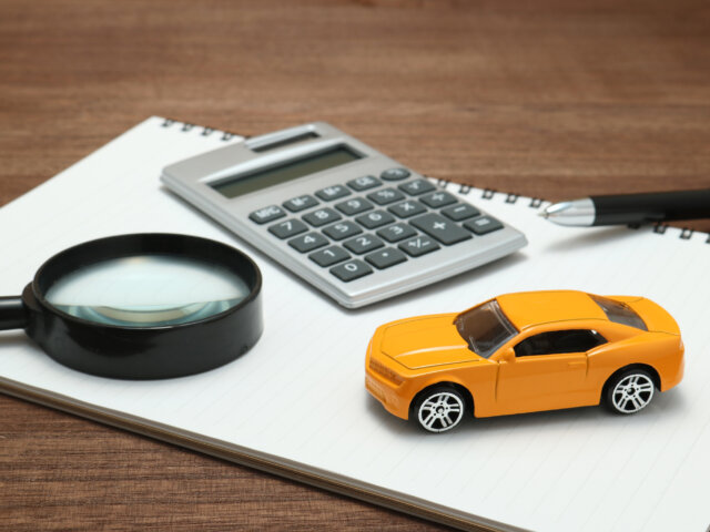 Toy car, magnifying glass, calculator, pen and notebook